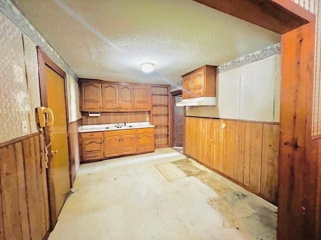 438 Atkins St, Sulphur Springs, TX 75482 - kitchen with wooden walls, brown cabinets, a wainscoted wall, and unfinished concrete flooring