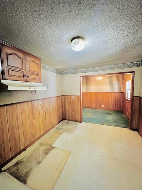 438 Atkins St, Sulphur Springs, TX 75482 - unfurnished room with wooden walls, a textured ceiling, baseboards, and wainscoting