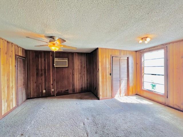 438 Atkins St, Sulphur Springs, TX 75482 - spare room featuring a wall mounted air conditioner, ceiling fan, wood walls, and light colored carpet