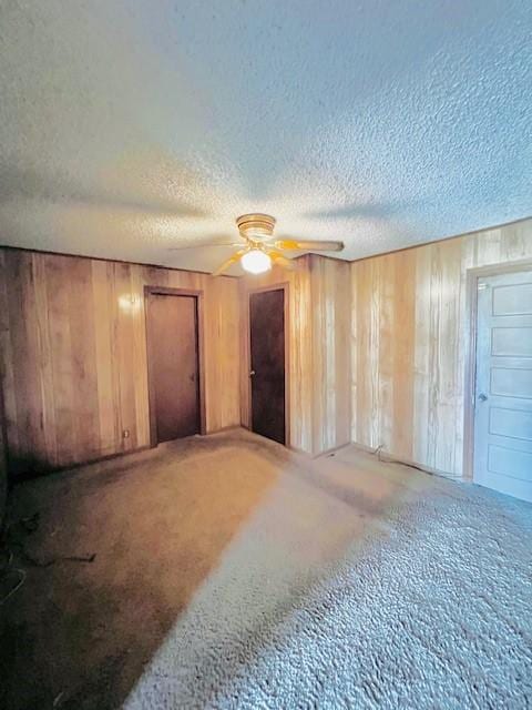 438 Atkins St, Sulphur Springs, TX 75482 - unfurnished bedroom featuring wooden walls, a textured ceiling, carpet flooring, and ceiling fan
