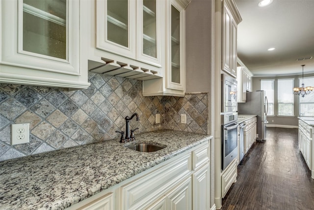 kitchen featuring light stone counters, a sink, dark wood-type flooring, baseboards, and appliances with stainless steel finishes