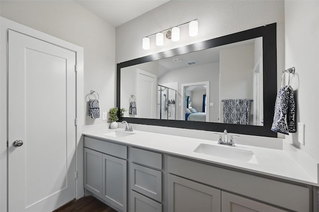 full bath featuring a stall shower, double vanity, a sink, and ensuite bathroom