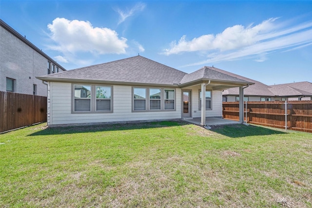 back of property featuring a lawn, a patio, a shingled roof, and a fenced backyard