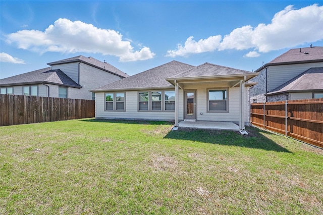 back of property featuring roof with shingles, a patio area, a yard, and a fenced backyard