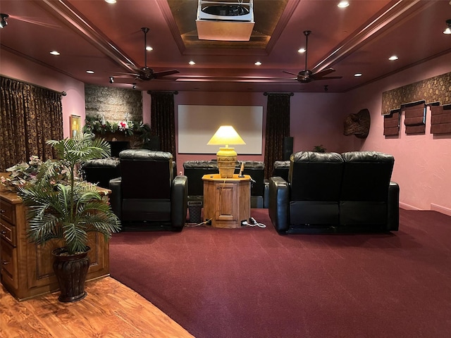 carpeted home theater with ceiling fan and a tray ceiling