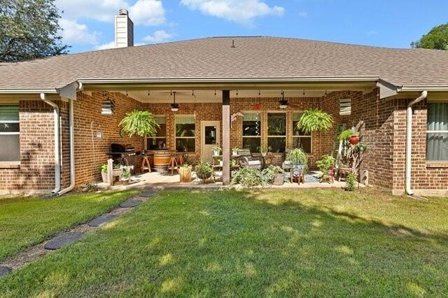 8450 Old Springtown Rd, Springtown, TX 76082 - rear view of house with brick siding, a yard, a ceiling fan, and a chimney