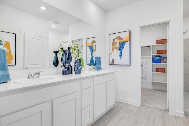 bathroom with wood finished floors, double vanity, a sink, and visible vents