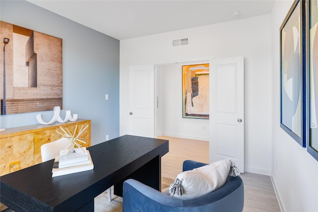 office space featuring wood finished floors, visible vents, and baseboards