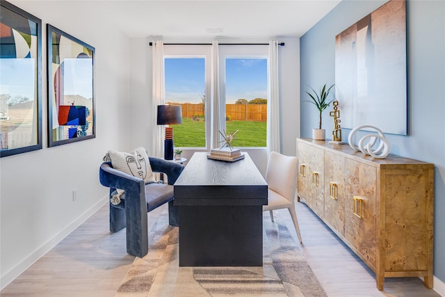 dining space with light wood-type flooring and baseboards