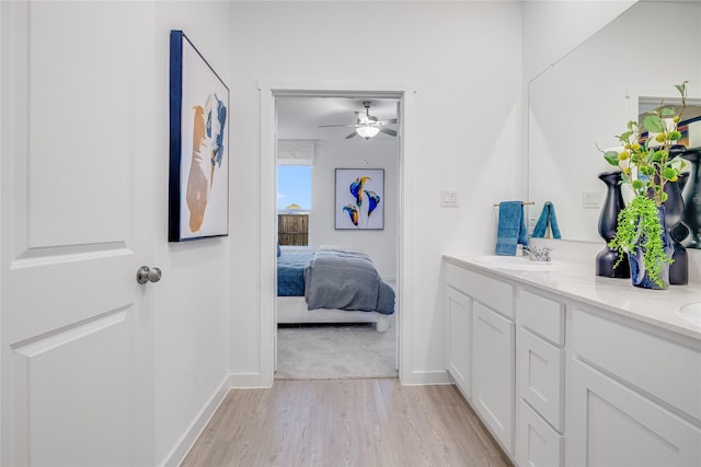 ensuite bathroom featuring baseboards, ceiling fan, double vanity, connected bathroom, and wood finished floors
