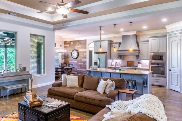 living area with visible vents, crown molding, baseboards, dark wood-type flooring, and ceiling fan with notable chandelier