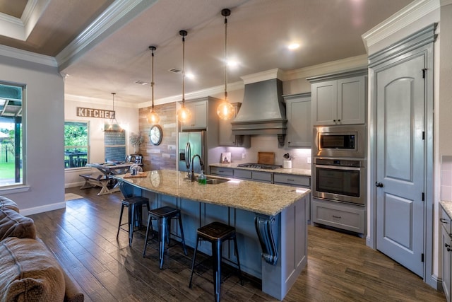 kitchen featuring premium range hood, gray cabinets, a sink, dark wood finished floors, and appliances with stainless steel finishes