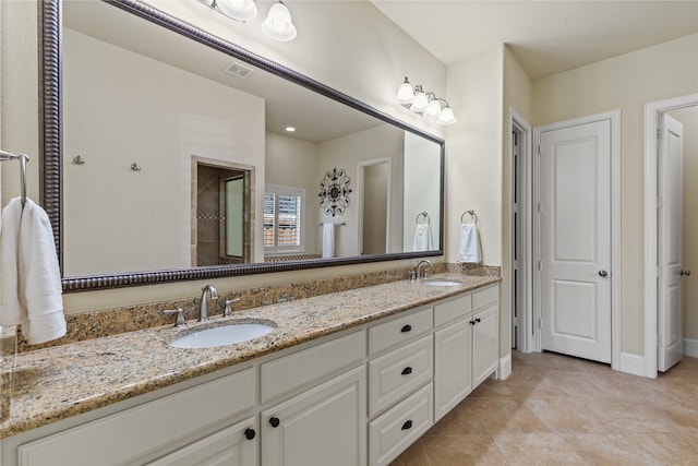 bathroom featuring tile patterned flooring, a sink, double vanity, and a tile shower