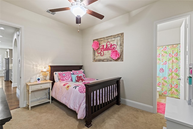 bedroom featuring visible vents, baseboards, carpet, a ceiling fan, and ensuite bath