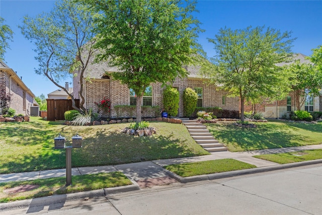 obstructed view of property with brick siding, fence, and a front yard