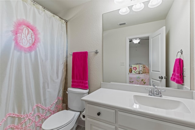 bathroom featuring visible vents, a textured wall, vanity, and toilet