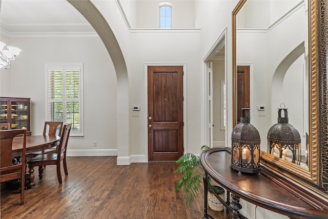 foyer with arched walkways, baseboards, dark wood-style floors, and ornamental molding