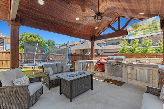 view of patio / terrace with a sink, a fenced backyard, a grill, a trampoline, and an outdoor kitchen