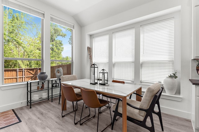 dining space with vaulted ceiling, baseboards, and light wood-style flooring