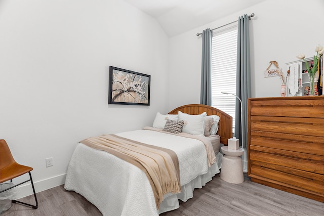 bedroom featuring lofted ceiling, wood finished floors, and baseboards