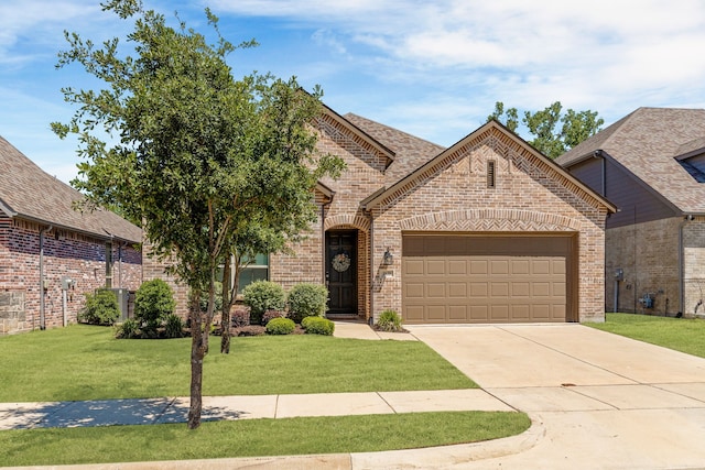 french provincial home featuring an attached garage, brick siding, driveway, and a front yard