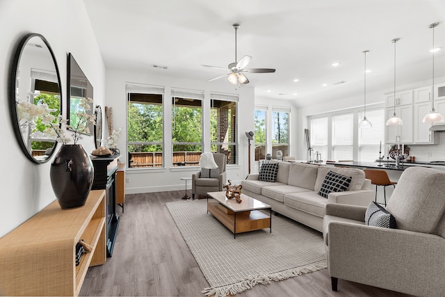 living area with recessed lighting, visible vents, a ceiling fan, light wood-type flooring, and baseboards