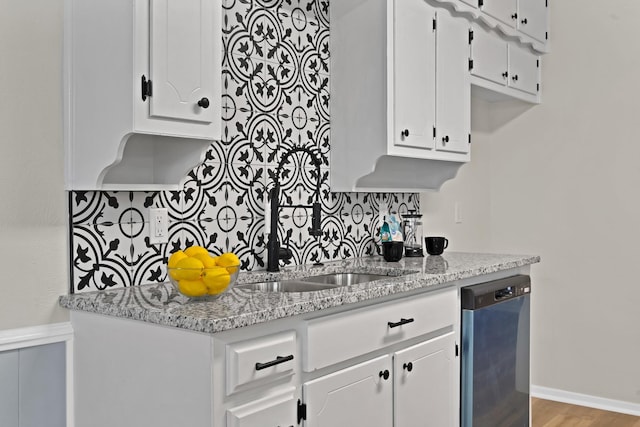 kitchen with light stone countertops, a sink, dishwasher, white cabinetry, and backsplash