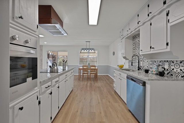 kitchen featuring black electric cooktop, a sink, dishwasher, light wood finished floors, and white cabinetry