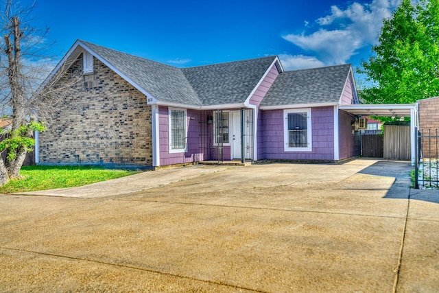 single story home with concrete driveway, fence, roof with shingles, and an attached carport