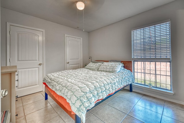 tiled bedroom with ceiling fan and multiple windows