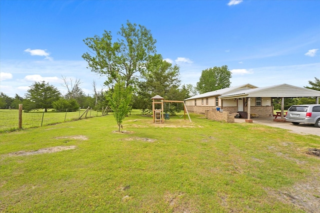 view of yard featuring fence, a carport, and a playground
