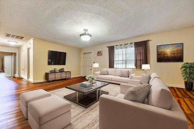living area with visible vents, baseboards, wood finished floors, and a textured ceiling