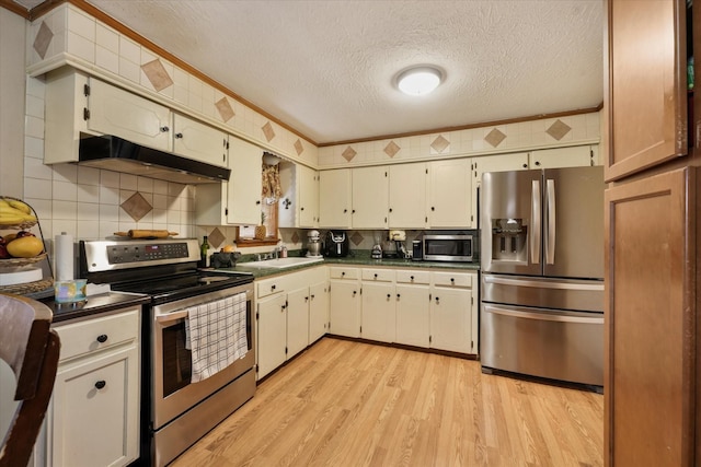 kitchen with under cabinet range hood, stainless steel appliances, dark countertops, light wood-style flooring, and a textured ceiling