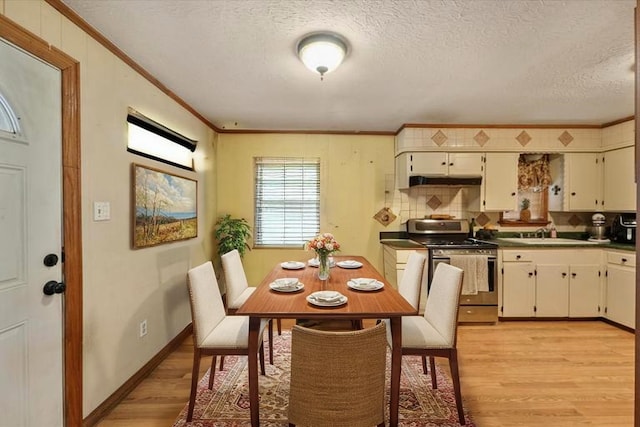 dining space featuring crown molding, a textured ceiling, and light wood finished floors