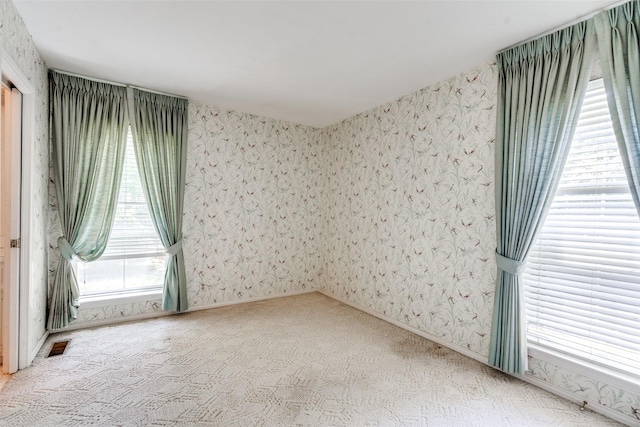 carpeted spare room featuring visible vents and wallpapered walls