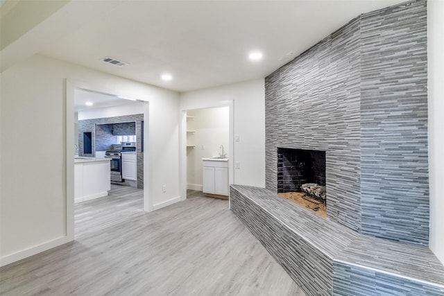 living room with recessed lighting, visible vents, light wood-style floors, baseboards, and a fireplace