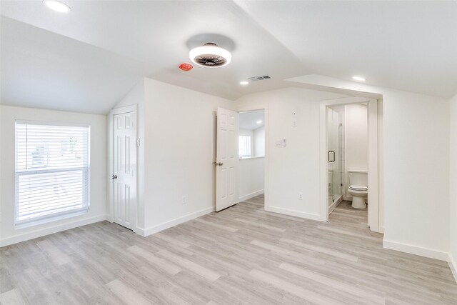 unfurnished bedroom featuring vaulted ceiling, light wood-style flooring, visible vents, and baseboards