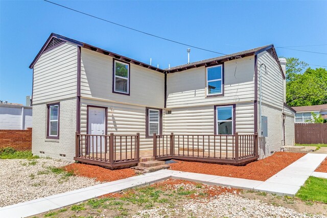 back of property with brick siding, crawl space, fence, and a deck