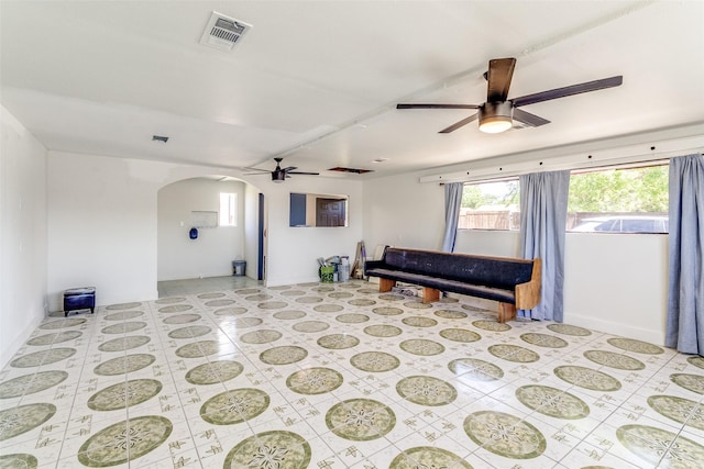 sitting room with arched walkways, visible vents, baseboards, and ceiling fan