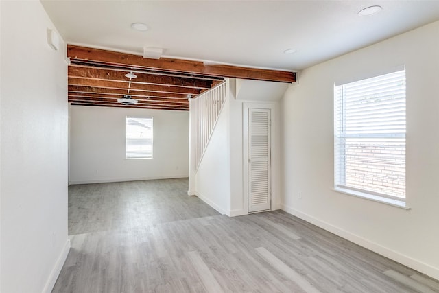 below grade area with stairs, wood finished floors, and baseboards