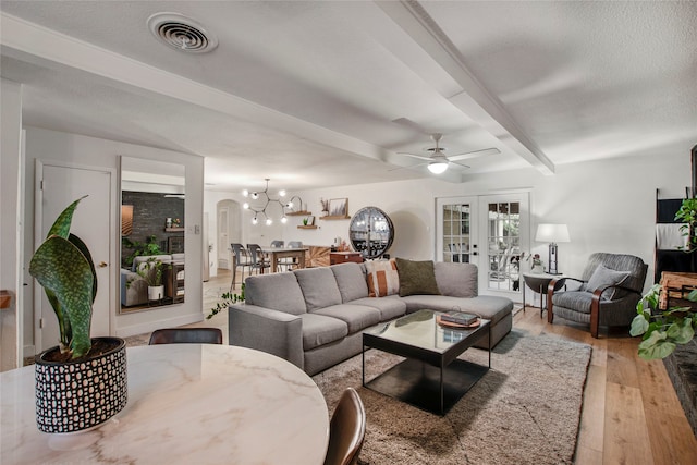 living room featuring visible vents, beam ceiling, ceiling fan with notable chandelier, and wood finished floors