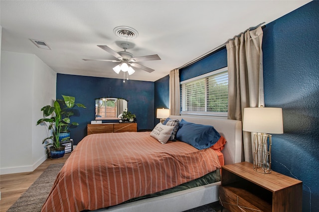 bedroom featuring baseboards, multiple windows, wood finished floors, and visible vents