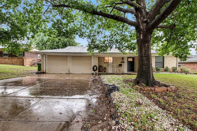 ranch-style home with concrete driveway, brick siding, an attached garage, and a front yard