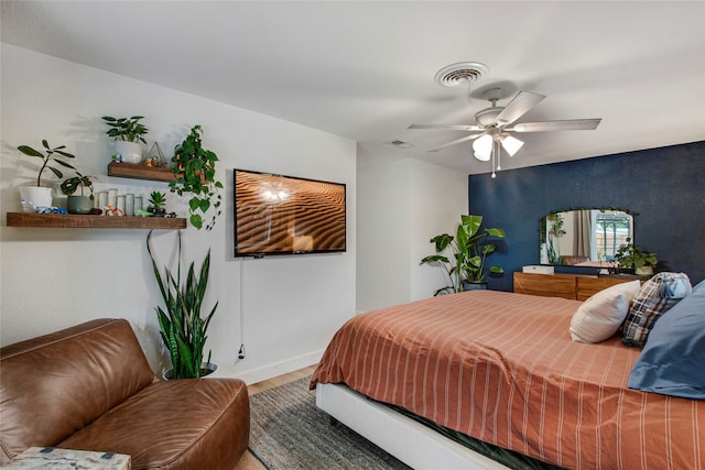 bedroom featuring visible vents, baseboards, ceiling fan, and wood finished floors