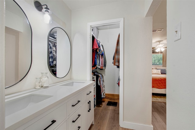 walk in closet with light wood-type flooring, a sink, and visible vents