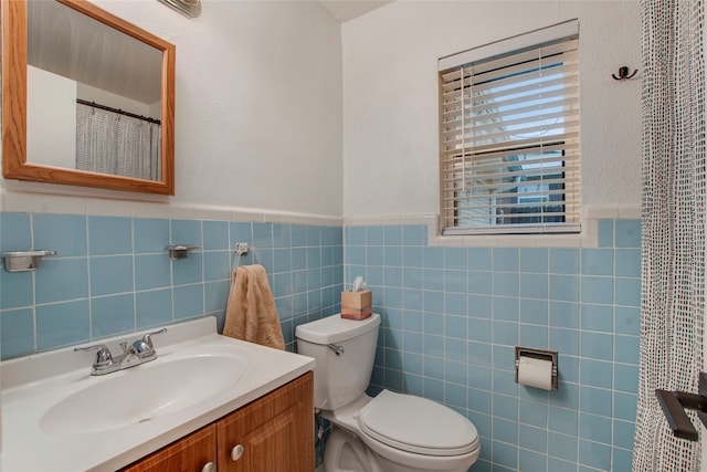 bathroom featuring tile walls, a wainscoted wall, vanity, and toilet