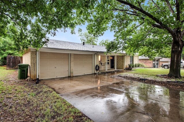 ranch-style house featuring a garage, fence, brick siding, a shingled roof, and driveway