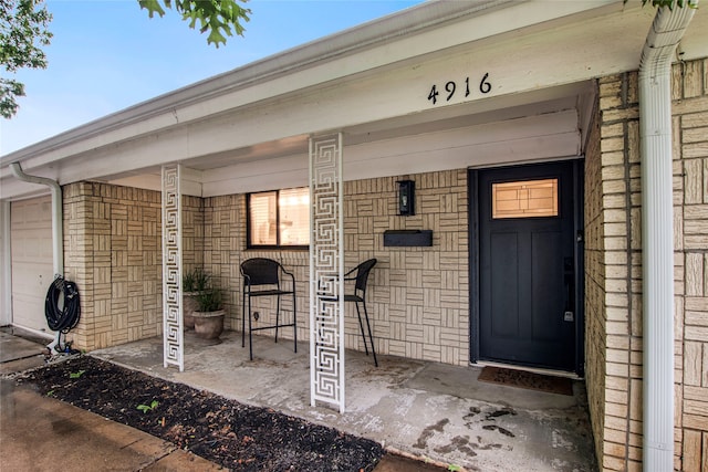 view of exterior entry featuring a porch and an attached garage
