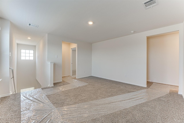 carpeted spare room featuring baseboards, visible vents, and recessed lighting