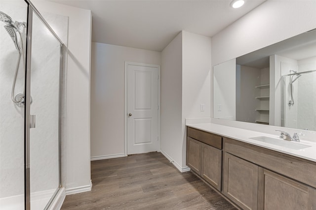 bathroom with baseboards, wood finished floors, vanity, and a stall shower